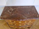 a marble top chest of drawers on a wooden floor