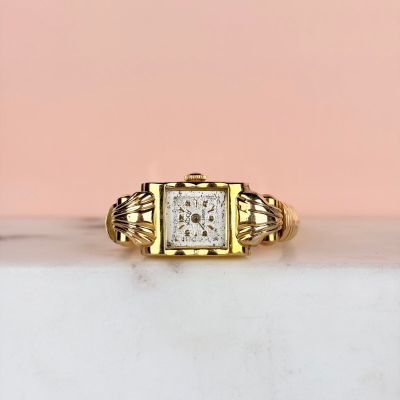 un gros plan d'une bague en or sertie d'un diamant carré au centre
