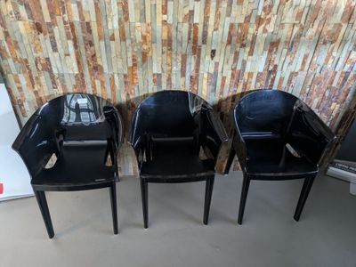 trois chaises noires placées les unes à côté des autres devant un mur