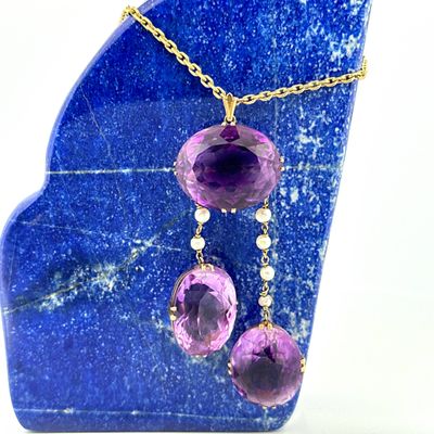 necklace with purple stones and gold chain on a blue marble slab