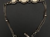 un vieux bracelet en argent avec une montre et un briquet posés sur une surface noire