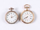 two gold pocket watches sitting side by side on a white surface