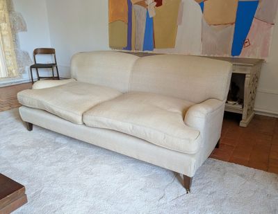 a white couch in a living room with a painting on the wall behind it