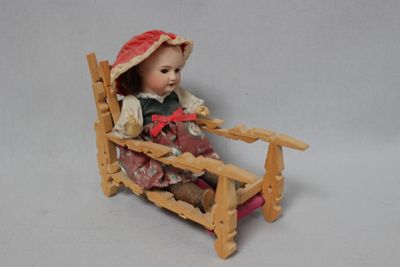 a doll sitting in a rocking chair with a hat on