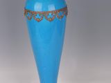 a blue vase sitting on a table with a gold rim