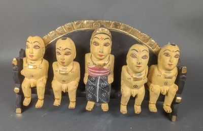 cinq figurines en bois représentant des personnes assises sur un banc
