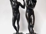 une paire de statues en bronze représentant un homme et une femme, posées sur des socles en marbre