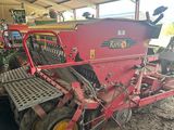 un tracteur rouge garé sur la terre battue
