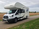 an rv parked on the side of a road next to a field