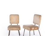 two wooden chairs with metal legs sitting next to each other on a white surface