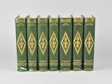 six green books are lined up in a row on a white surface