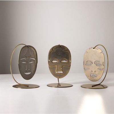 trois masques métalliques posés les uns sur les autres sur une table