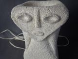 a white vase with a face on it on a table
