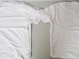 two white t - shirts sitting on top of a table next to each other