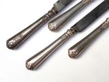 three silver plated knives and a knife on a white surface