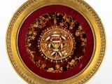 une assiette dorée et rouge ornée d'un motif doré et rouge