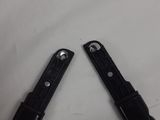 two black plastic knives are laying on top of a white table