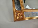 a mirror with a gold frame on a white wall