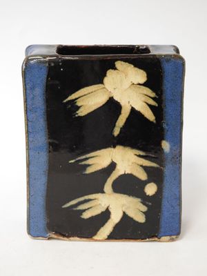 a black and blue vase with a yellow flower on it