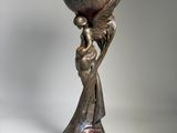 bronze sculpture of a woman holding an egg on a pedestal
