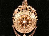 une image représentant un pendentif en or orné d'une horloge