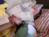 a pile of folded towels and blankets on a bed