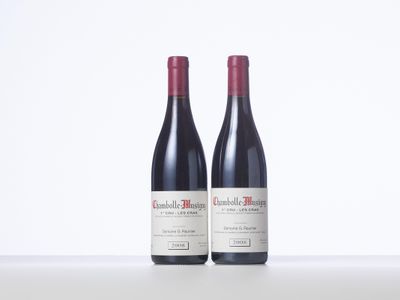 two bottles of red wine sitting on top of a white table