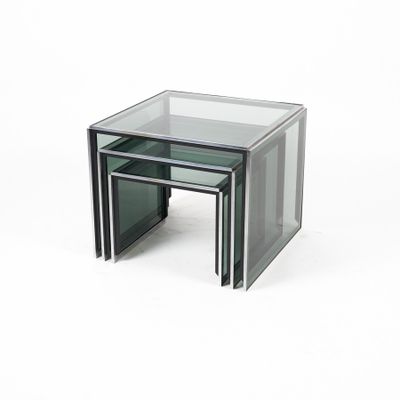 trois tables gigognes en verre posées sur une surface blanche, sur fond blanc