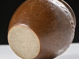 a brown vase sitting on a table with a black background