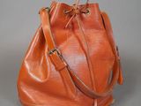 an orange leather bucket bag sitting on top of a gray surface