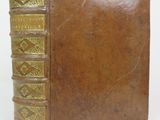 an old brown book with gold trim sitting on top of a white surface