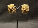 pair of gold plated earrings on a stand against a black background