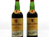 deux bouteilles de vin posées l'une à côté de l'autre sur une surface blanche