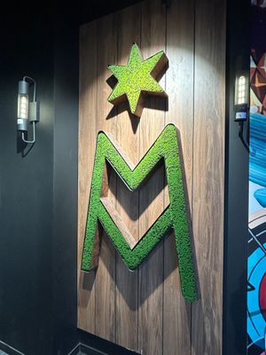 a wooden sign with a green m on it