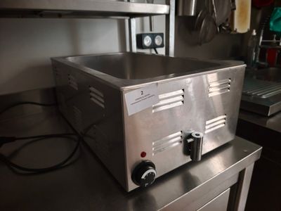un plan de travail en acier inoxydable sur lequel est posé un grille-pain, dans une cuisine