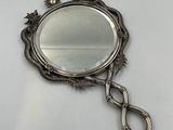 a close up of a mirror on a white surface with a metal handle
