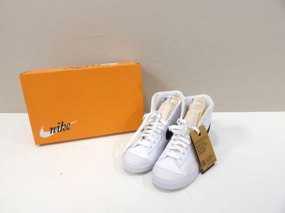 white nike tennis shoes with orange box on a white table