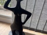 a black vase sitting on a wooden floor in front of a window
