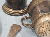 a silver cup with a spoon and spoon rest on a table