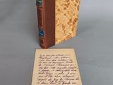 un vieux livre posé sur une table à côté d'une feuille de papier