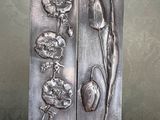 deux sculptures métalliques représentant des fleurs, posées sur une table avec un mur en arrière-plan