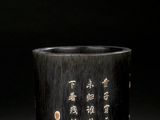 an old black vase with writing on it sitting on a table