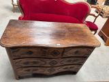 une commode en bois avec un canapé rouge en arrière-plan