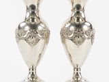 deux vases en argent posés l'un sur l'autre sur une surface blanche