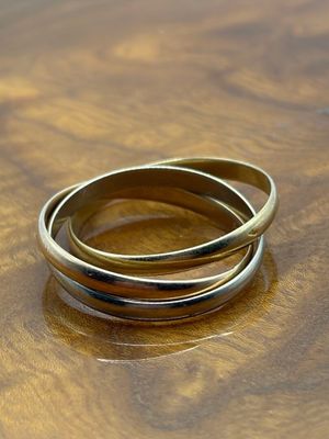 trois bagues en or posées sur une table en bois, sur fond blanc