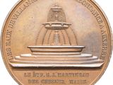 a bronze coin with a fountain on top of it