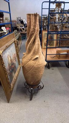 un grand vase posé sur un socle devant un tableau