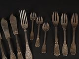 a lot of forks and spoons on a black table