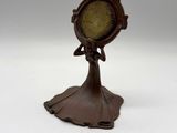 an image of a small clock on a stand on a white surface
