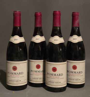 four bottles of red wine are lined up on a table